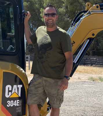 Bill Tolley, owner-operator of Dragon Equipment Rentals, standing next to a CAT 304E mini excavator in Las Vegas
