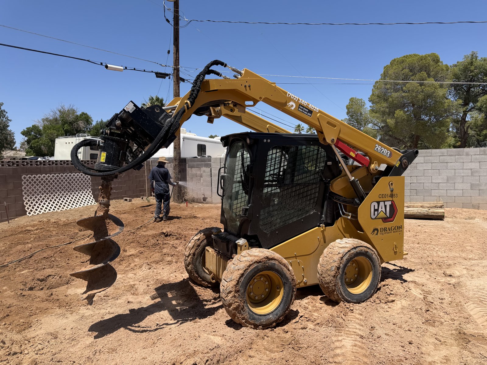 CAT 262D3 Skid Steer with auger attachment raised high, full auger bit visible, ready for post-hole drilling — Dragon Equipment Rentals Las Vegas