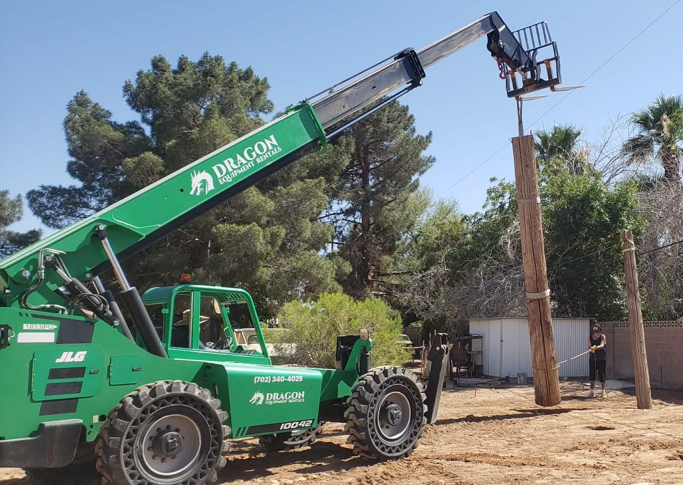 JLG 10042 Telehandler with Dragon Equipment Rentals branding lifting a wood utility pole, 10,000 lb capacity, 42 ft lift — Las Vegas